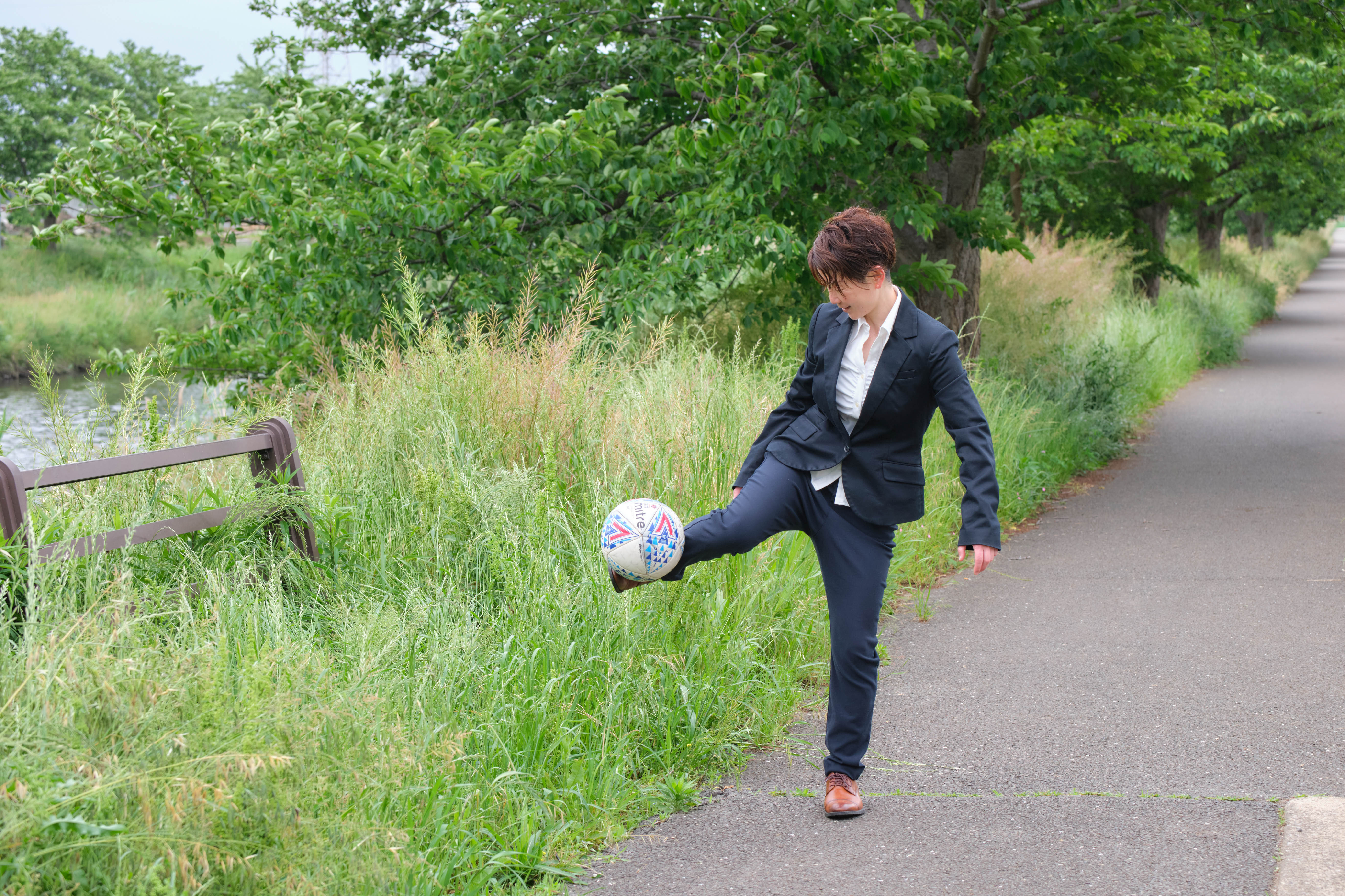 スーツ姿でサッカーボールをリフティングするきゃお